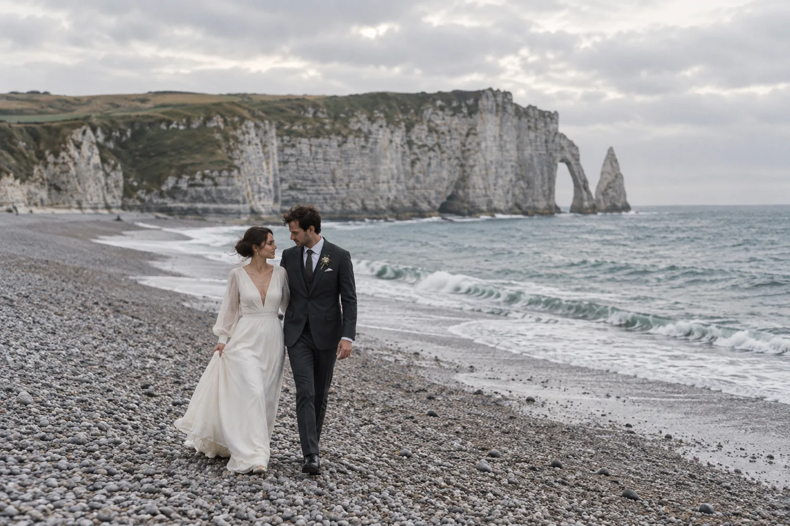 The couple walking along a pebble beach in Normandy