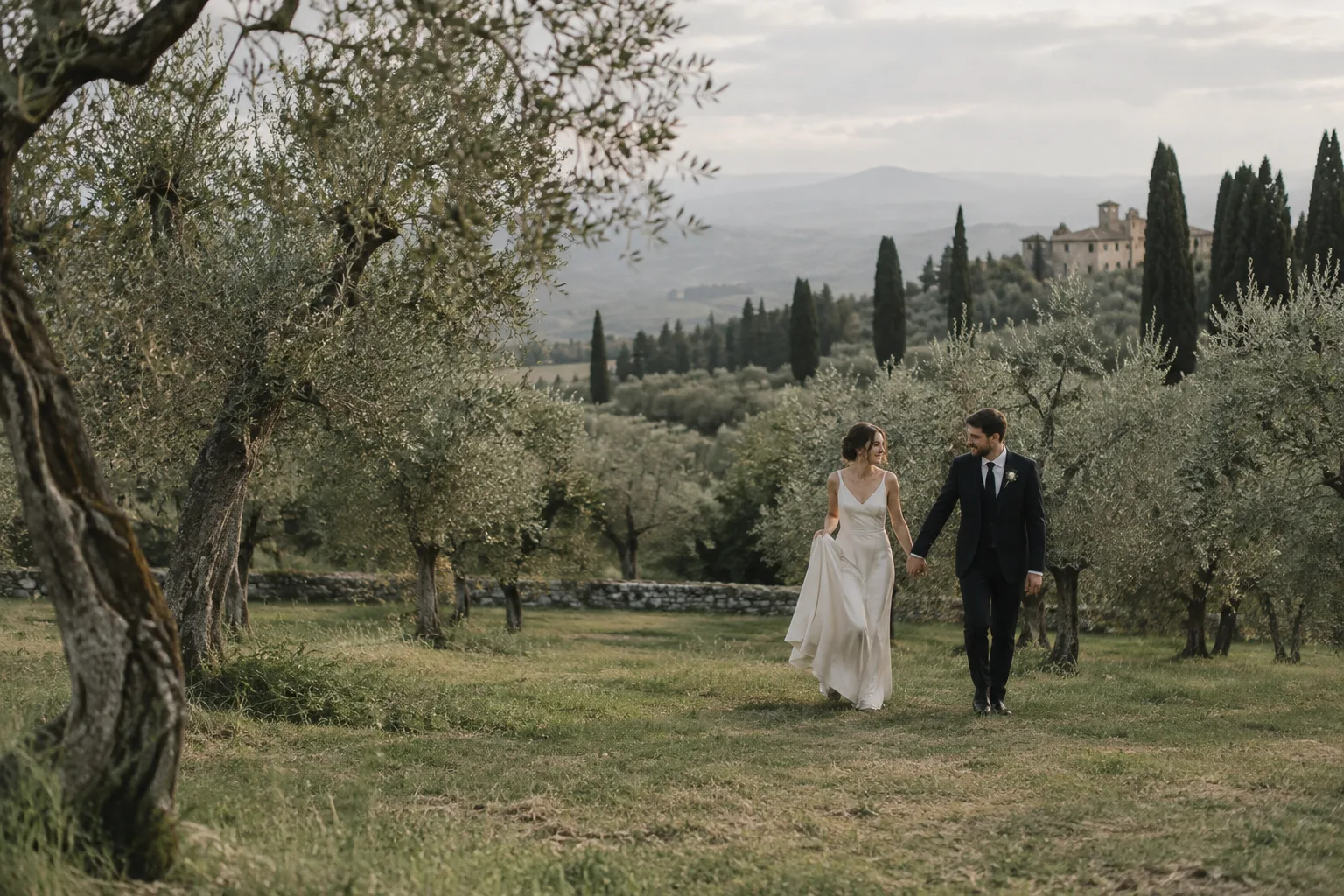A wedding couple walking together through a sunlit olive grove